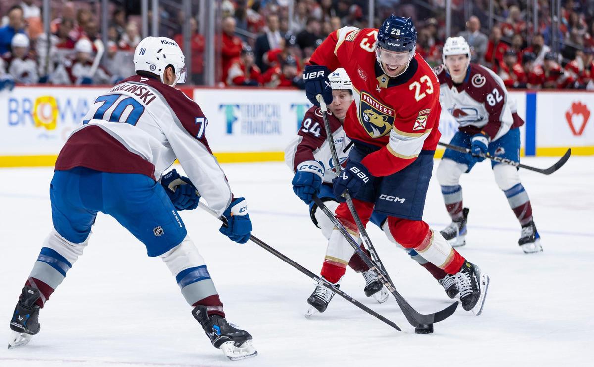 Florida Panthers center Carter Verhaeghe (23) shoots the puck as Colorado Avalanche defenseman Sam Malinski (70) and left wing Joel Kiviranta (94) defend in the first period of their NHL game at Amerant Bank Arena on Saturday, Nov. 23, 2024, in Sunrise, Fla.