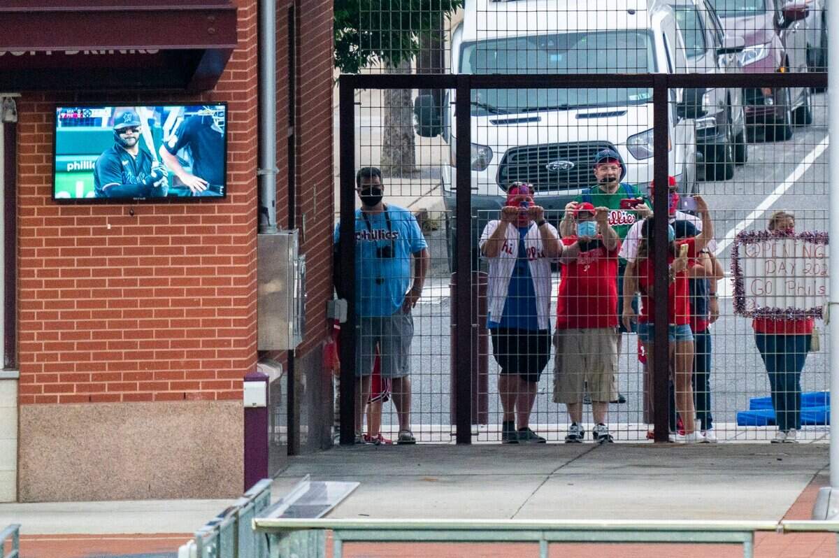 Philadelphia Phillies’ fans watch from the gate outside of the stadium just past center field during the first inning of a baseball game against the Miami Marlins, Friday, July 24, 2020, in Philadelphia. (AP Photo/Chris Szagola)