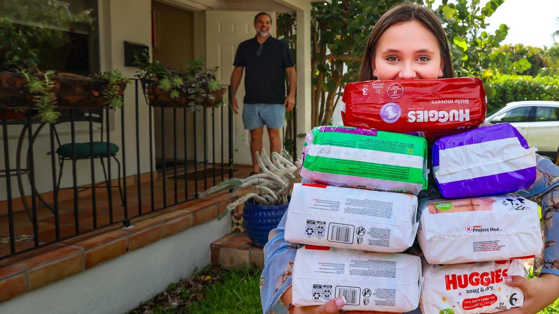 Mark Boomer, left, smiles as he watches his daughter Mina carry a stack of diapers to donate to moms at the C.O.P.E. Center South, a Miami-Dade public school for pregnant and parenting teenagers.