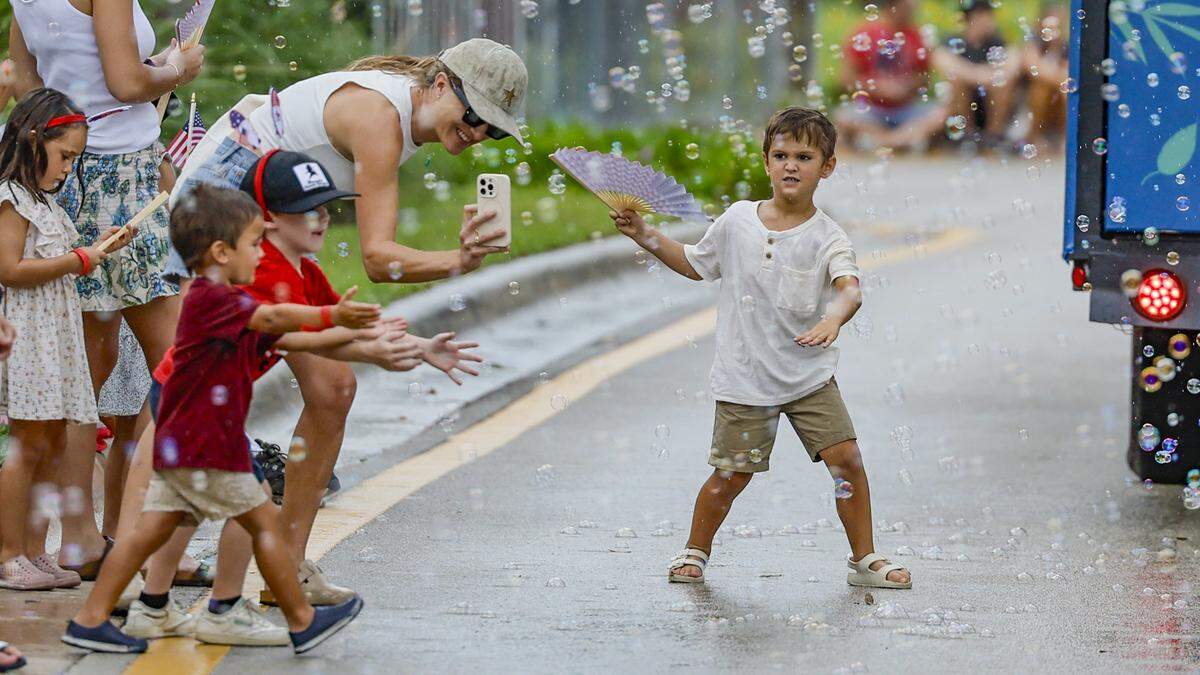 Parade goers chase bubbles as they celebrate Independence Day during the 66th Annual Key Biscayne Fourth of July Parade on Key Biscayne, Florida on Friday, July 4, 2025.