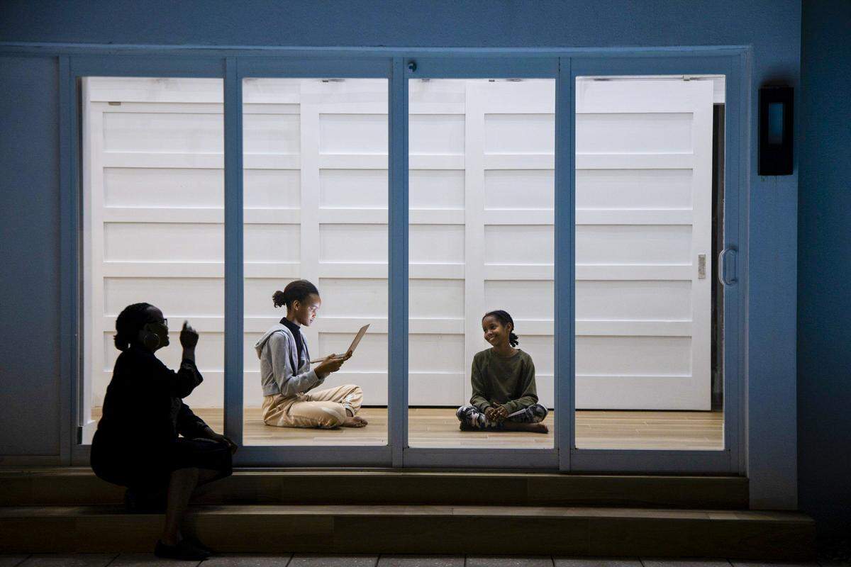 Haitian-American author Edwidge Danticat and daughters — Mira, center, and Leila — have been sheltering in place and practicing social distancing for the past three weeks at their Miami residence. In this image, Danticat tries to get Leila’s attention as she sits in her yard during the COVID -19 pandemic on Wednesday, April 1, 2020.