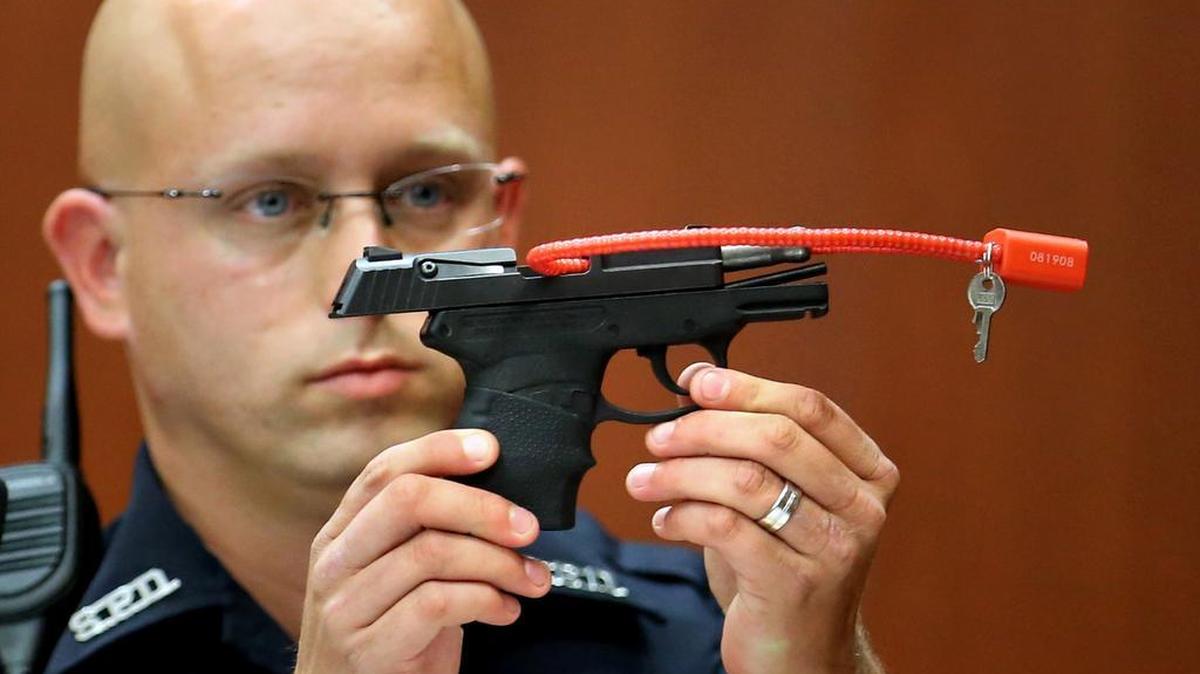 In this June 28, 2013, file photo, Sanford police officer Timothy Smith holds up the gun that was used to kill Trayvon Martin.