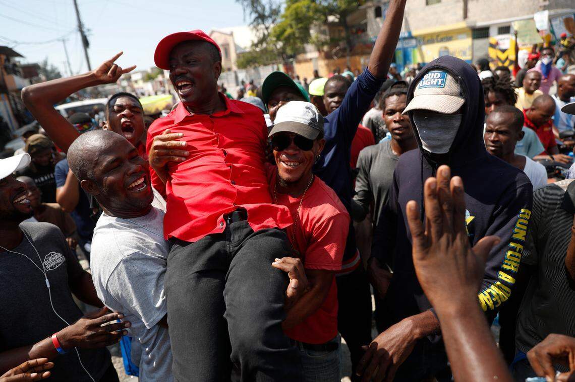 Opposition politician Jean-Charles Moïse is lifted by supporters who came to greet him from the roadside, as he leads several hundred protesters through the Tabarre neighborhood toward the United States embassy in Port-au-Prince, Haiti, Thursday, Oct. 17, 2019.