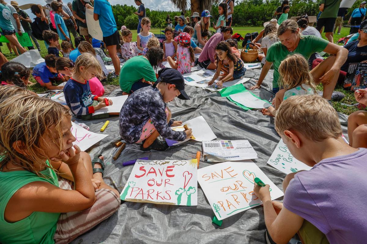 School children Kai Boero, 6, and Marcus Weisel, 8,create posters as they join protesters with Keep Florida State Parks Wild-Defend Oleta State Park against the Florida Department of Environmental Protection’s plan to add pickleball courts, cabins, and a disc golf course to Oleta River State Park in North Miami Beach, Florida on Tuesday, August 27, 2024.