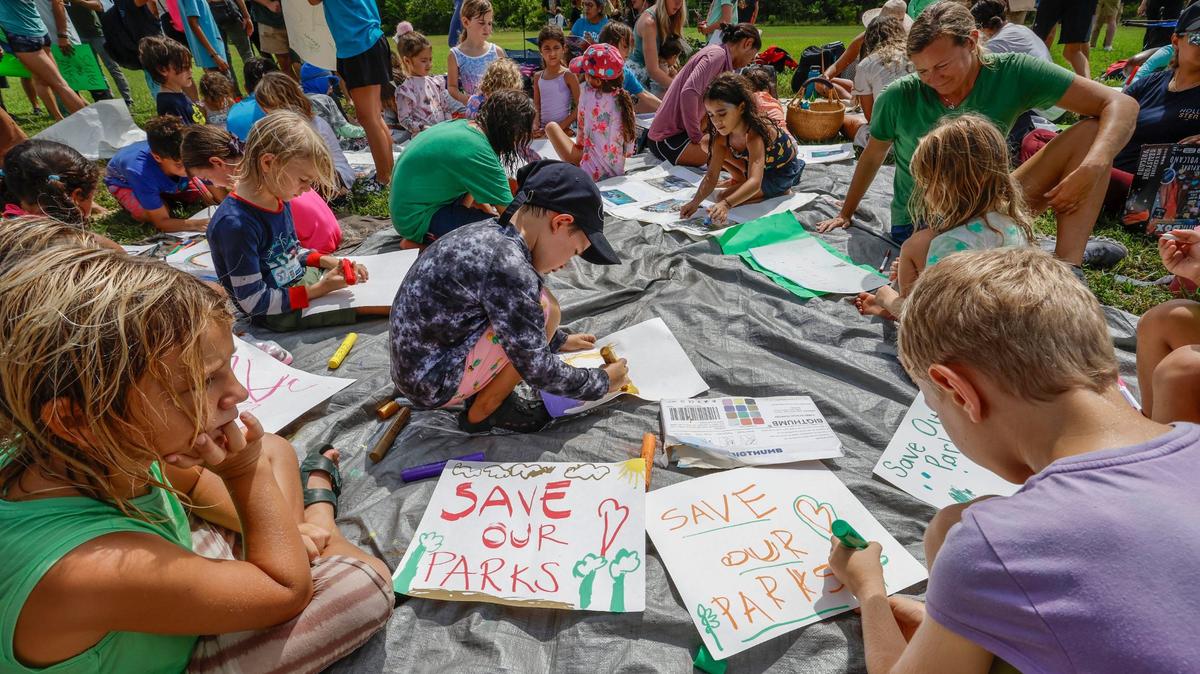 School children Kai Boero, 6, and Marcus Weisel, 8, join protesters against the state plan to add pickleball courts, cabins, and a disc golf course to Oleta River State Park.