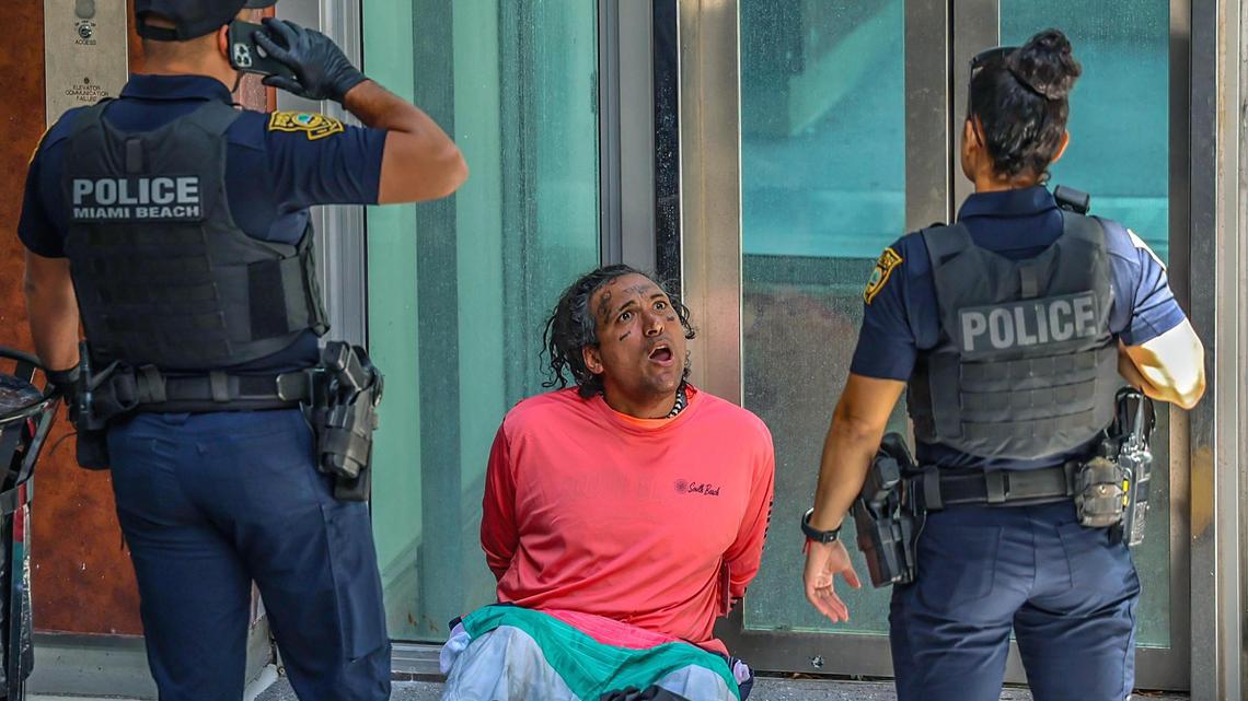 Miami Beach Police officers talk to a homeless person seating behind the CVS Store located at 322 Lincoln Road a couple of hours after the Florida Governor Ron DeSantis signed the HB 1365 bill “to keep Florida’s streets safe”, at a press conference at a restaurant in South Beach on Tuesday March 20, 2024.