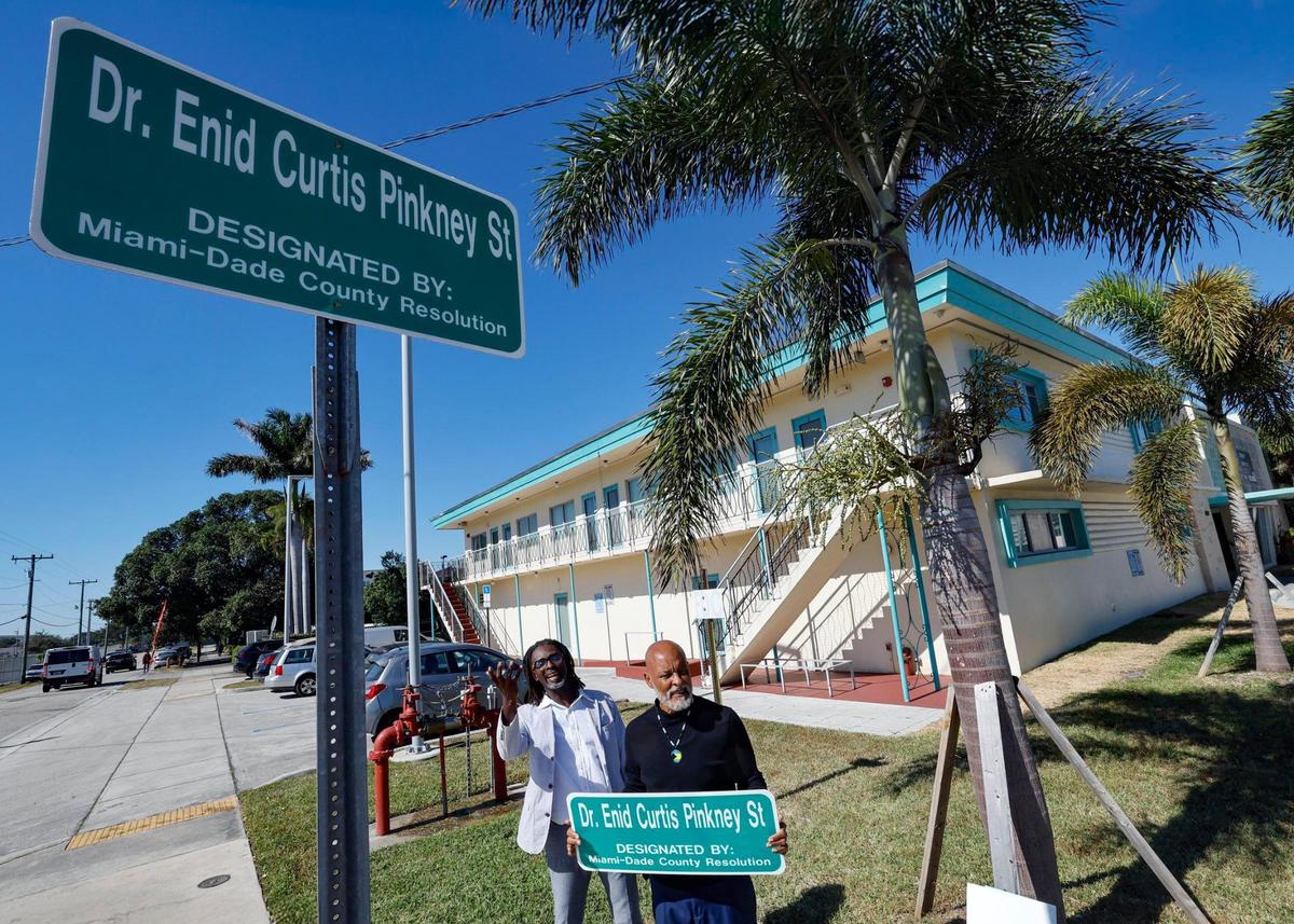 Brothers Dak Knowles and Gary Allen, left to right, stand under the street sign named after Allen’s aunt Miami historian Dr. Enid Curtis-Pinkney, after the street naming ceremony at the Hampton House in Miami, Florida, on Friday, November 22, 2024.