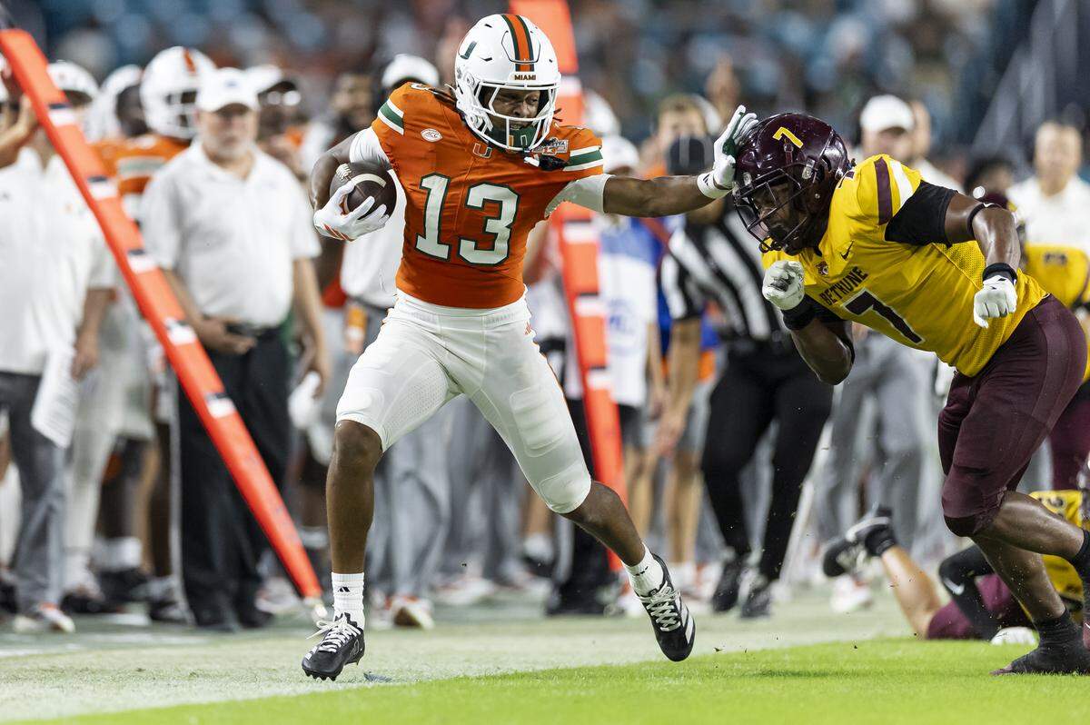 Miami Hurricanes wide receiver Daylyn Upshaw (13) stiff arms Bethune-Cookman Wildcats linebacker Stephen Sparrow (7) in the second half of their NCAA football game at Hard Rock Stadium on Saturday, Sept. 6, 2025, in Miami Gardens, Fla.