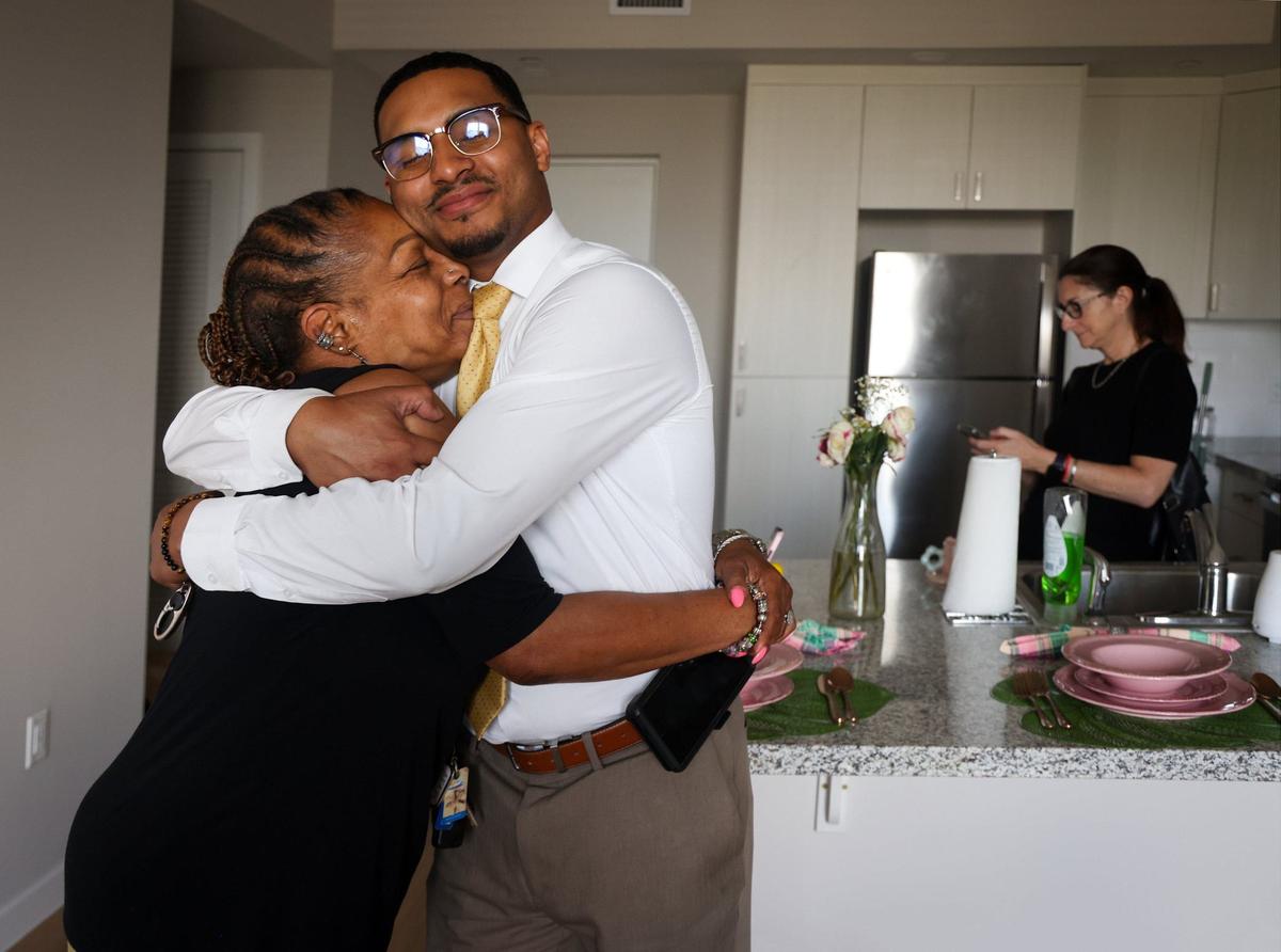 Marie Honoré-Riguad, who has battled with mental health issues, is grateful for the support of her son, Israel Riguad, center, during a quick visit as she moves into her new apartment along other residents with mental health disabilities at the Foot Print to Success Clubhouse on Thursday, June 6, 2024, in Pembroke Pines, Florida.