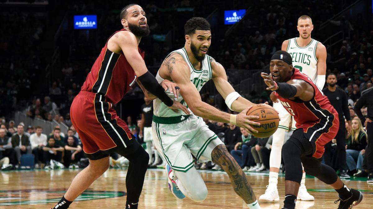 Boston Celtics forward Jayson Tatum (0) drives to the basket between Miami Heat forward Caleb Martin (16) and center Bam Adebayo (13) during the second half in game one of the first round for the 2024 NBA playoffs at TD Garden.