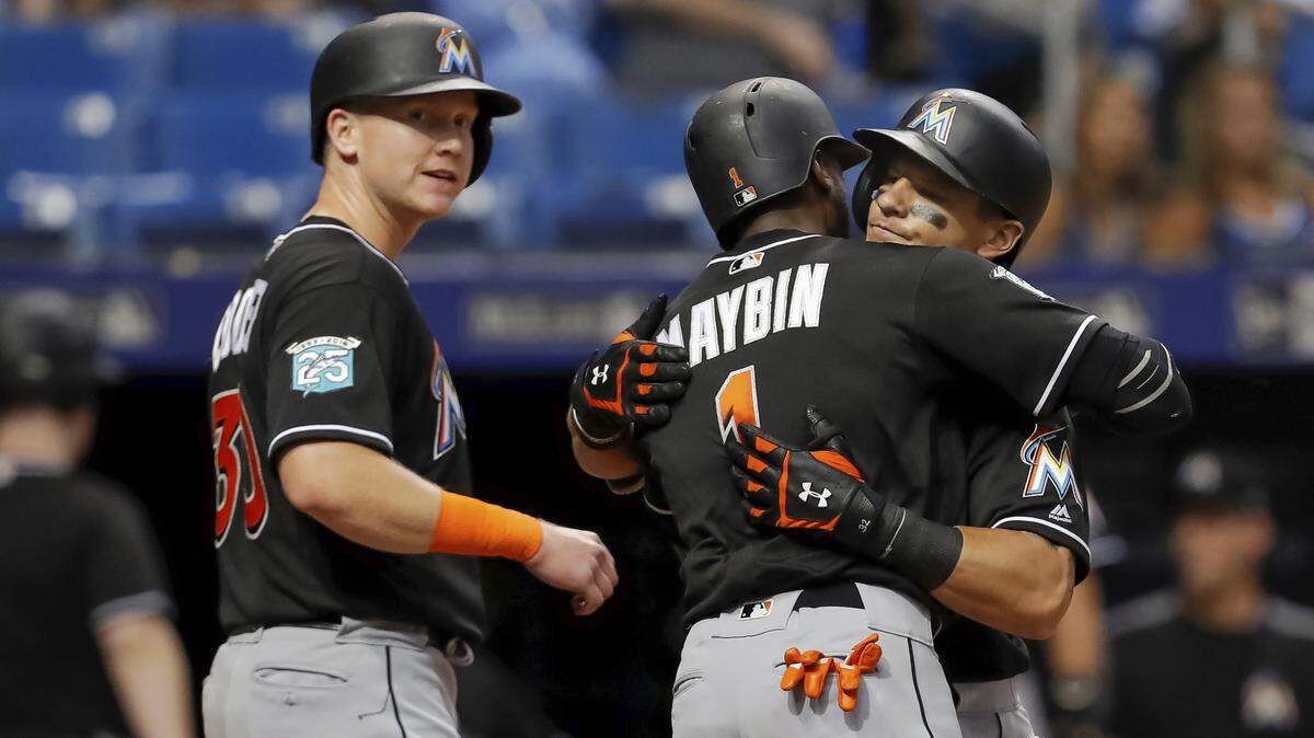 Miami Marlins' Derek Dietrich, right, is congratulated by Cameron Maybin (1) and Garrett Cooper after his three-run home run scored them all during the seventh inning of a baseball game against the Tampa Bay Rays on Friday, July 20, 2018, in St. Petersburg, Fla. (AP Photo/Mike Carlson)