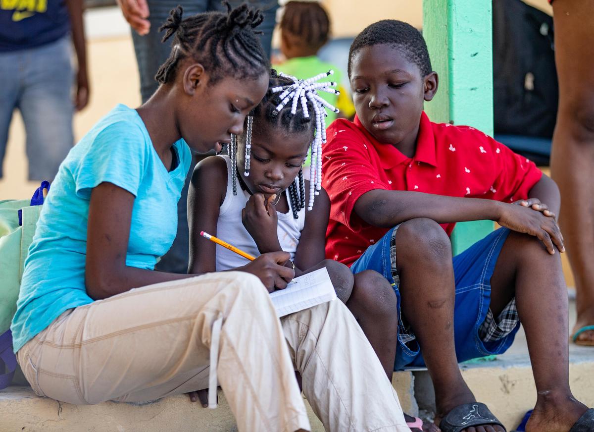 Chelsea Michel, 12, helps Alicia St. Remy, 6, with her vocabulary words as JC Emmanuel Michel, 9, looks on, on Saturday, Sept. 7, 2019. The children have been living at a storm shelter in Marsh Harbour, Abaco, since Hurricane Dorian ravaged the Bahamas.