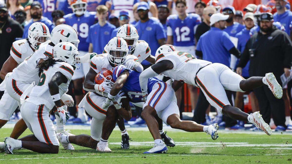 Miami Hurricanes defensive lineman Elijah Alston (11) and Miami Hurricanes linebacker Wesley Bissainthe (31) and fellow teammates take down Florida Gators wide receiver Eugene Wilson III (3) in the first quarter at Ben Hill Griffin Stadium in Gainesville, Florida, on Saturday, August 31, 2024.