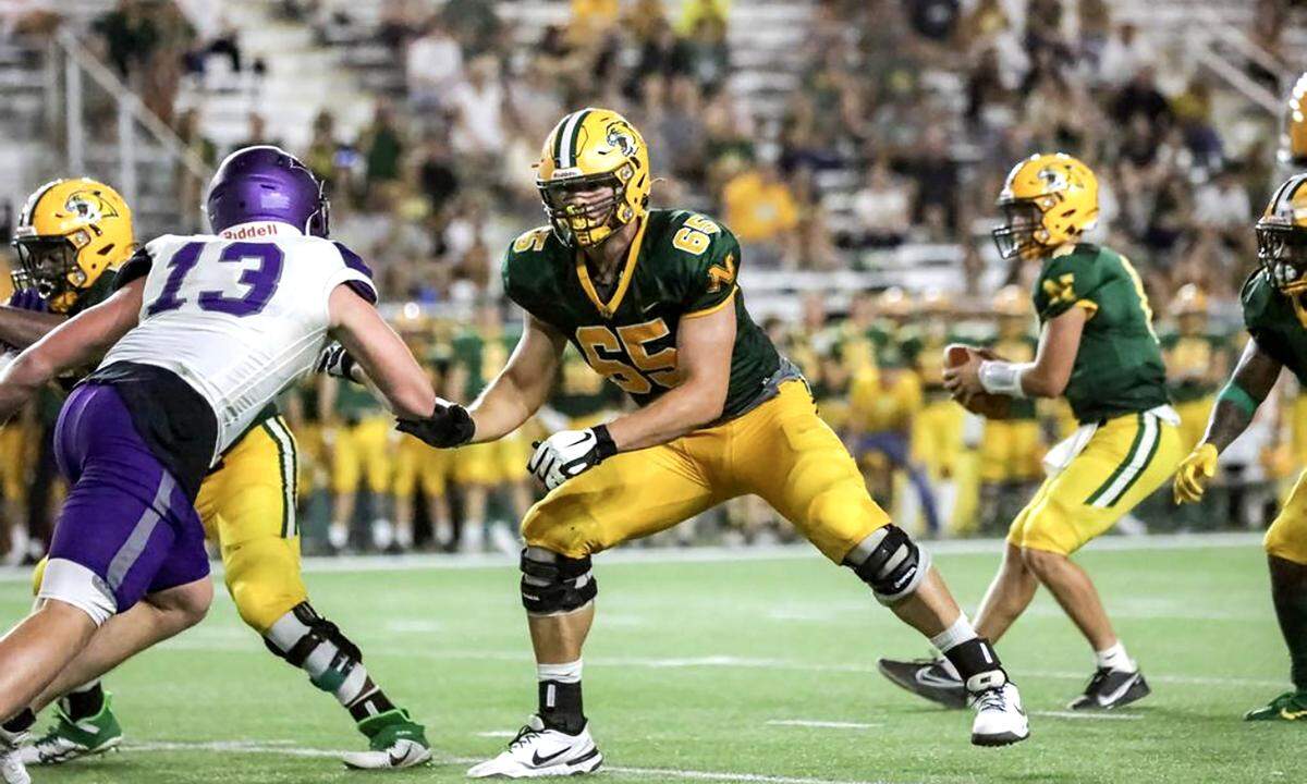 Northern Michigan University football lineman Jake Witt, center, blocks for the Wildcats’ offense during a game last fall at the Superior Dome in Marquette.