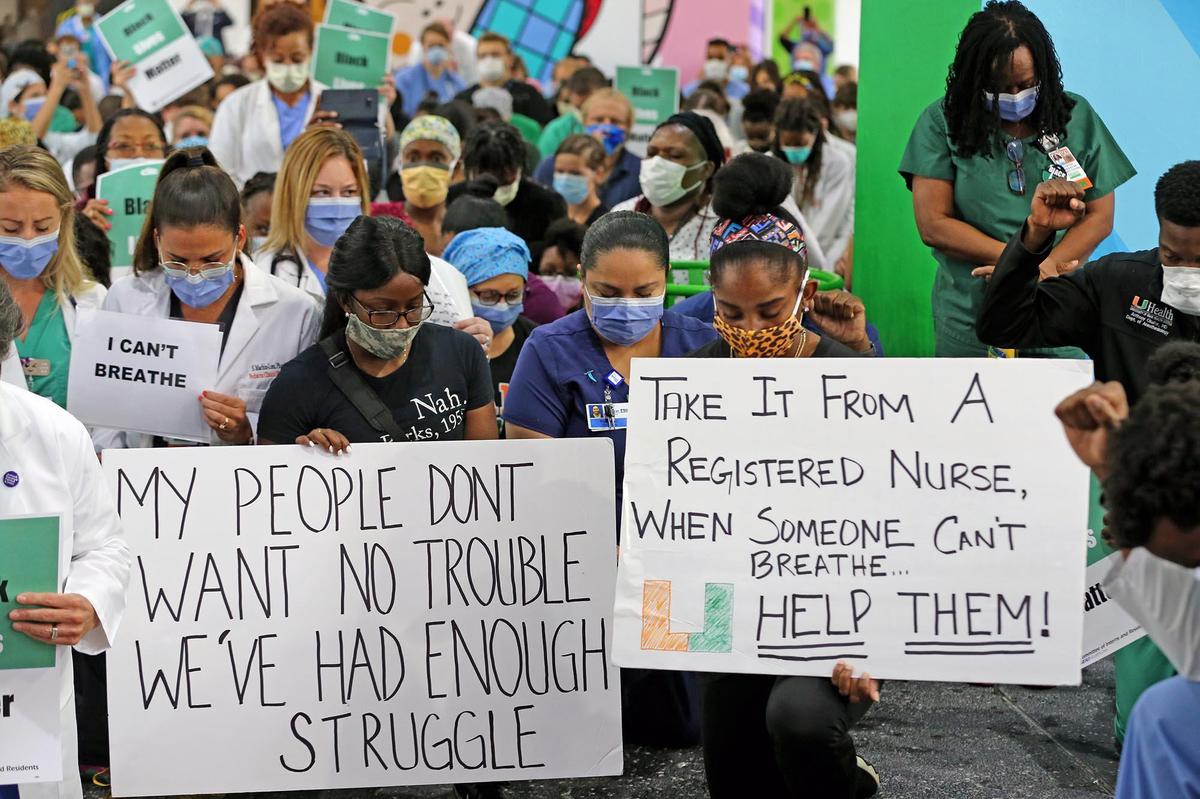 Healthcare workers at Jackson Memorial Hospital and other activists kneel for nine minutes to reflect on the death of George Floyd June 4, 2020.