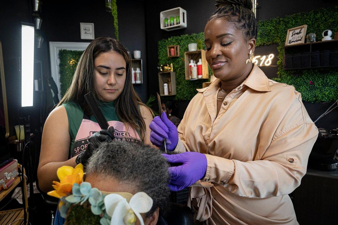 Hadassa Felix, a Haitian American hairstylist and entrepreneur, right, works on a client’s matted hair with her assistant, Marlyn E. Felix, who served in the Army, runs Love 518 salon in Little Havana.