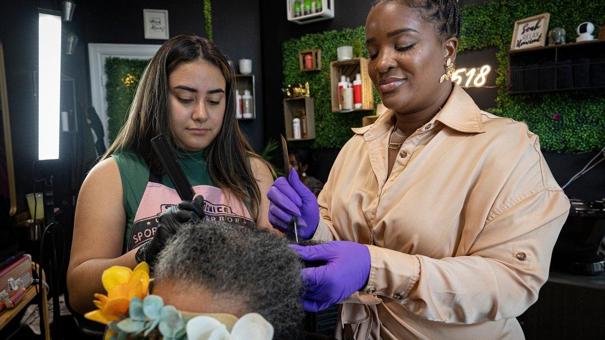 Hadassa Felix, a Haitian-American hair stylist and entrepreneur, right, works on a clients matted hair with her assistant, Marlyn E, on Wednesday, May 24, 2023, inside her shop called Love 518 in Little Havana. Donald Trump’s words about Haitians have shaken South Florida.