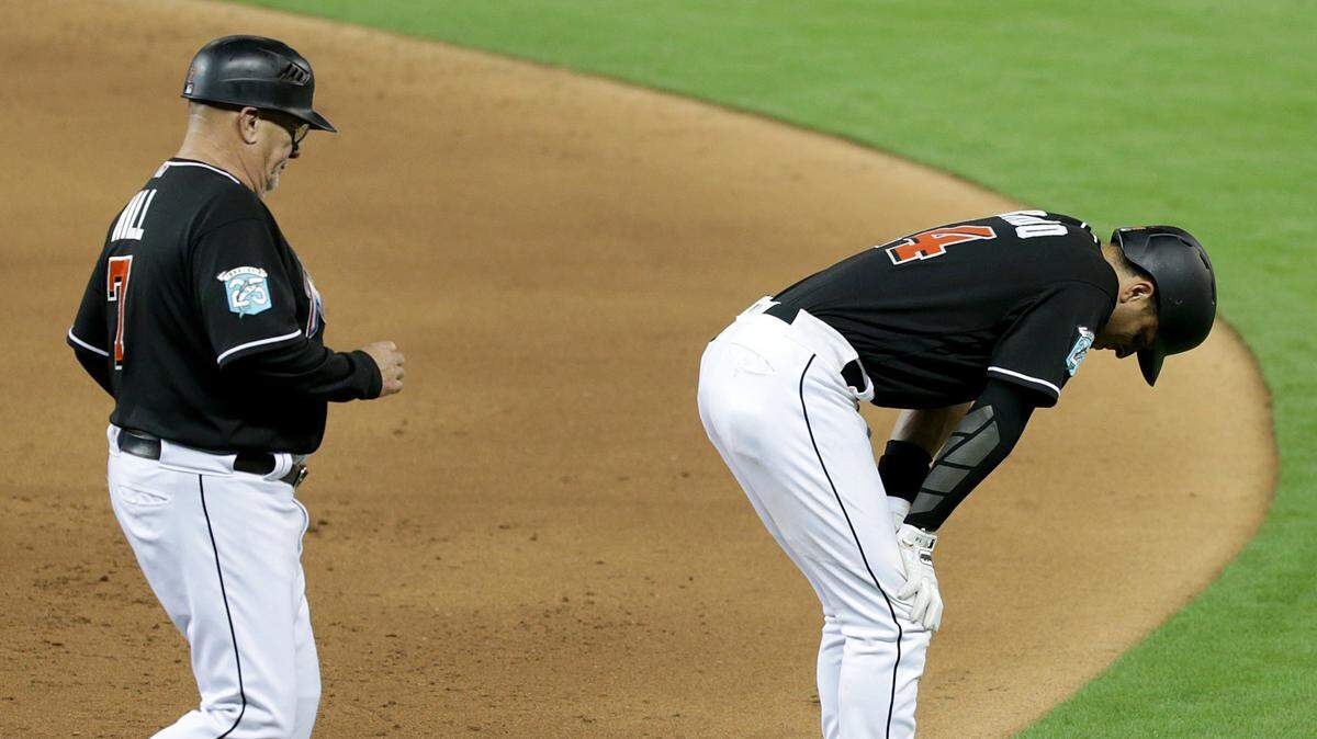Marlins first base coach Perry Hill runs to check third baseman Martin Prado who got hurt after reaching to first base on error by Washington's short stop Trea Turner in the sixth inning of the Miami Marlins vs Washington Nationals game at Marlins Park, Friday, May 25, 2018.