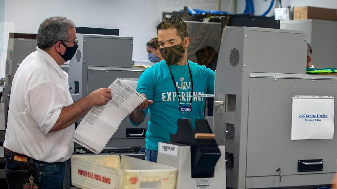 Miami-Dade County Elections department employees input mail-in and early voting ballots into the tabulation machines ahead of the 2020 general election.