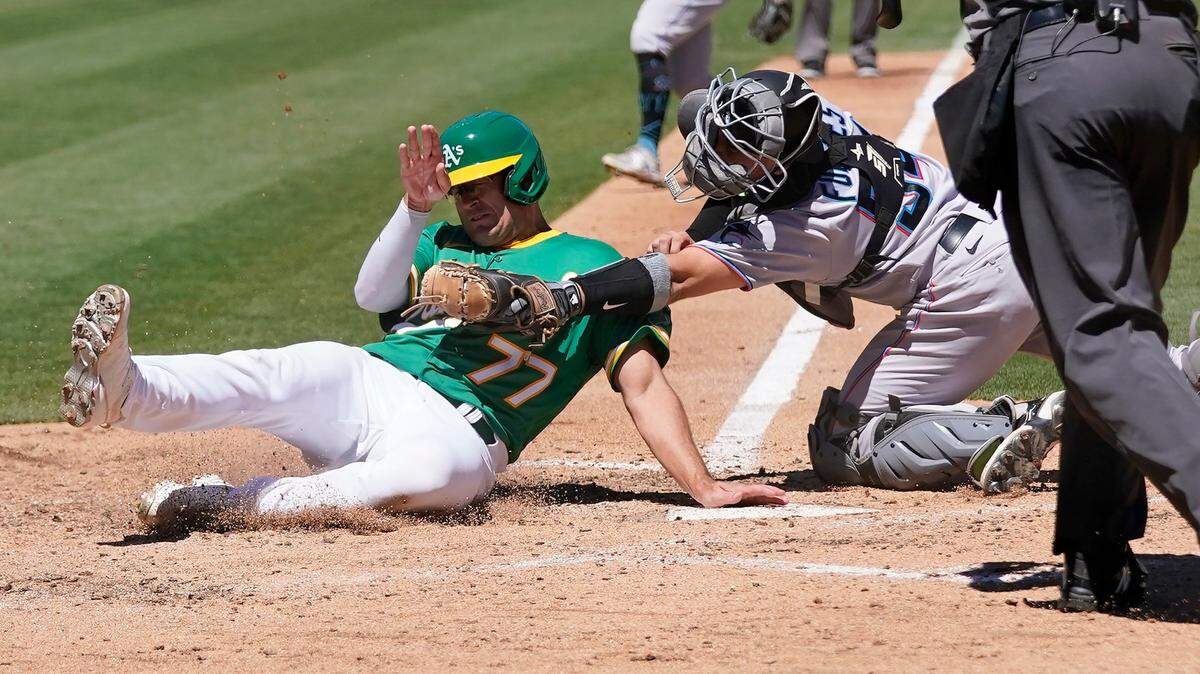 Oakland Athletics’ Jonah Bride, left, is tagged out at home by Miami Marlins catcher Nick Fortes during the sixth inning of a baseball game in Oakland, Calif., Wednesday, Aug. 24, 2022. (AP Photo/Jeff Chiu)