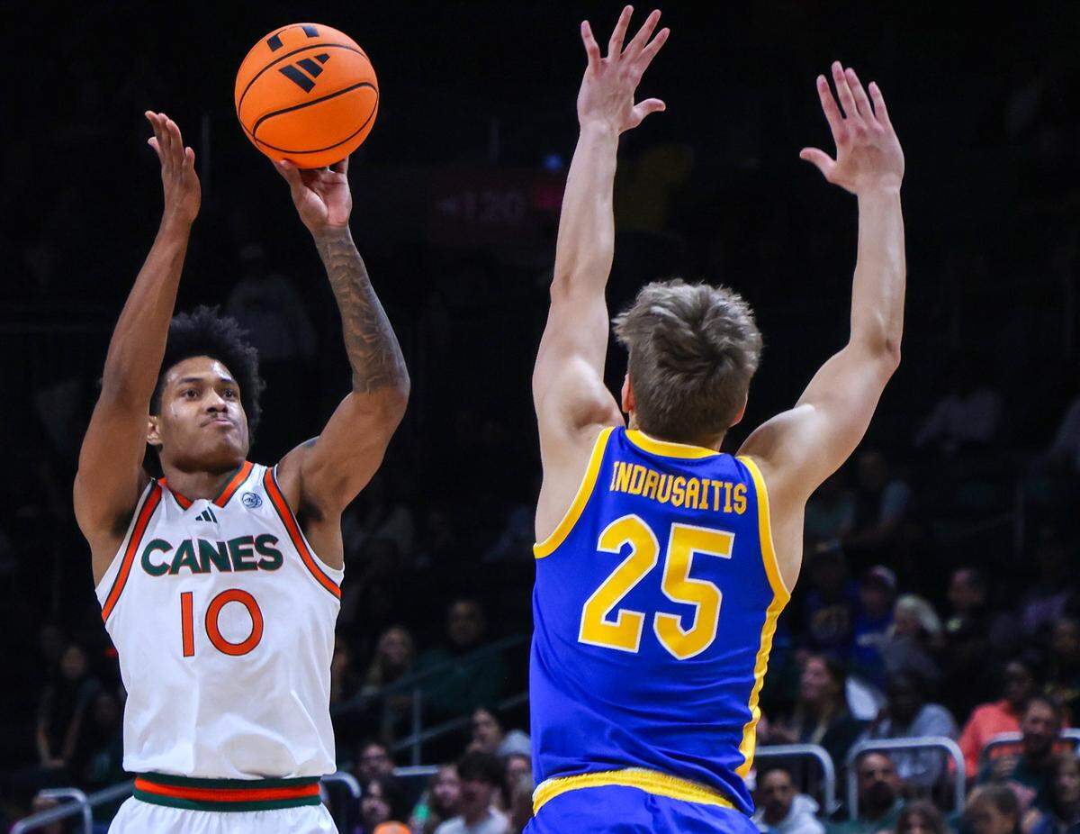 UM guard Tru Washington, left, takes the jumper over Pitt guard Nojus Indrusaitis, right, in the first half as University of Miami (11-2) Men's basketball played against Pittsburgh (7-6) in the ACC opener at the Watsco Center in Coral Gables, Florida, on Sunday, December 14, 2025.