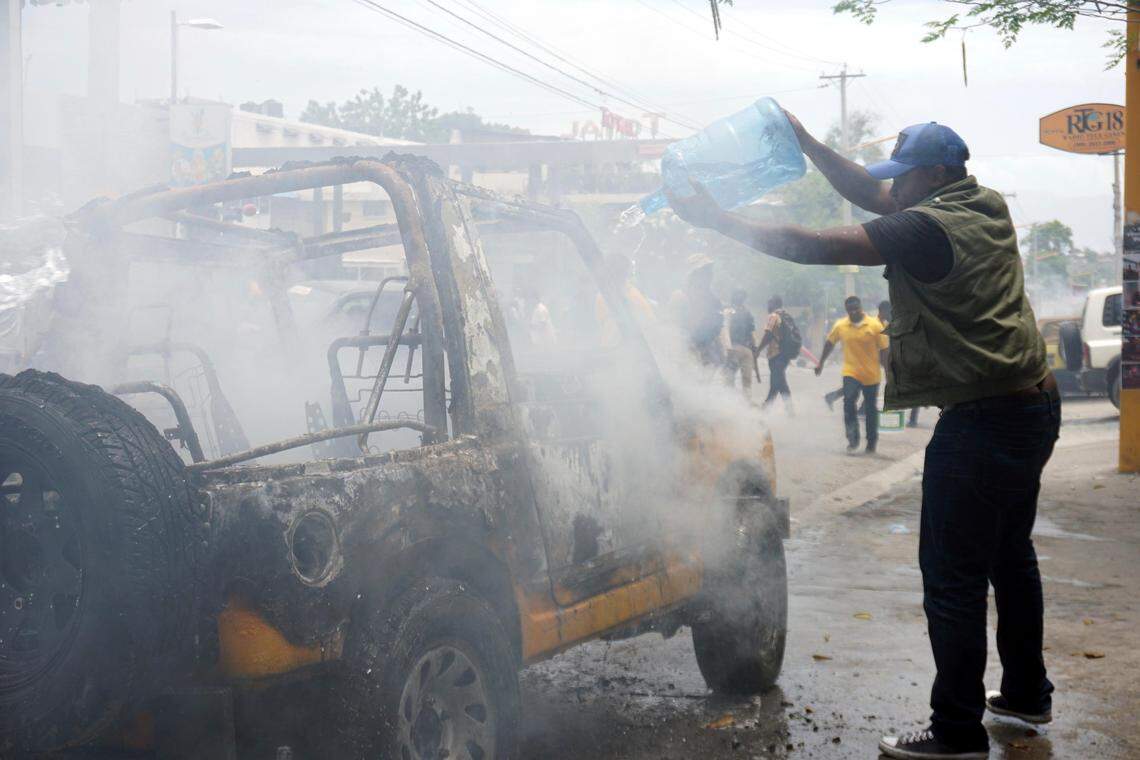 A local journalist tries to throw water on a burning vehicle that belongs to Radio Télé Ginen in Port-au-Prince, Haiti, Monday, June 10, 2019.