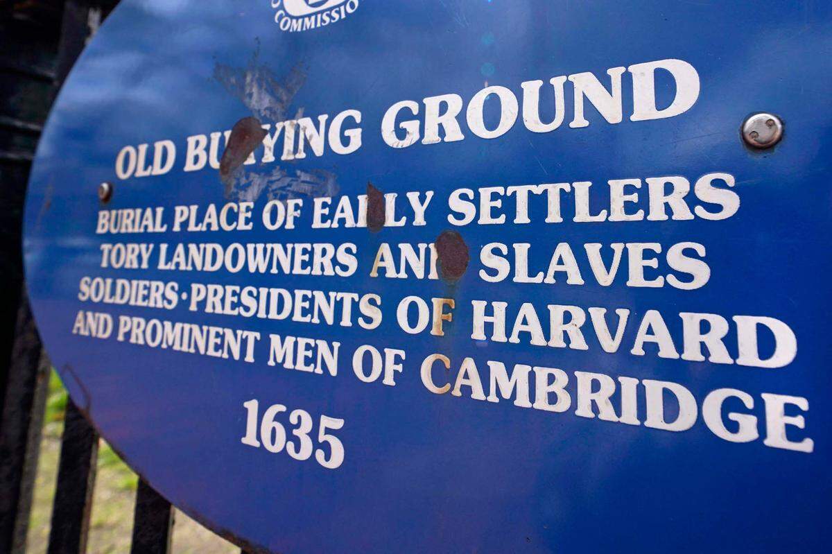 A sign on a gate leading to the Old Burying Ground lists the resting place of Harvard community leaders, and some of the people they enslaved, just outside Harvard Yard, Wednesday, April 27, 2022, in Cambridge, Mass. In Harvard’s pledge to atone for its ties to slavery, it identified dozens of people who were enslaved by the university’s first leaders and faculty members. Hundreds of years later, their living descendants are estimated to number in the thousands, including some who lived and worked in the Boston area without knowing their family connection to the Ivy League school.
