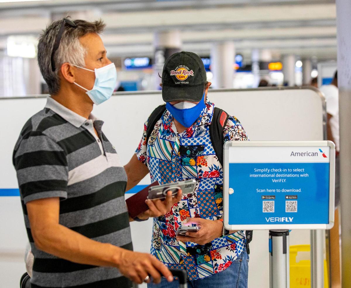 Two travelers skip the long lines to check in, using VeriFLY, a smartphone app that lets people upload documentation proof of negative COVID test or vaccine proof, before their international flight from Miami International Airport in Miami, Florida, on Monday, June 7, 2021.