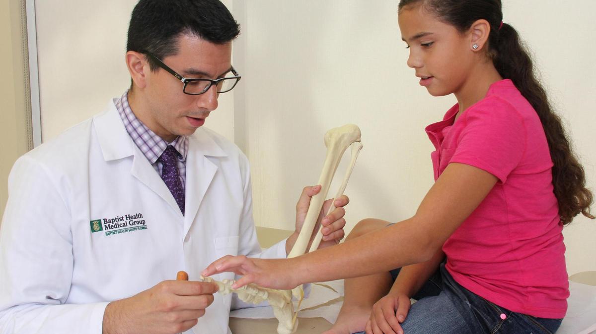 Dr. Roger Saldana, pediatric orthopedic surgeon with Miami Orthopedics & Sports Medicine Institute, part of Baptist Health South Florida, examines Bianca Zabala.