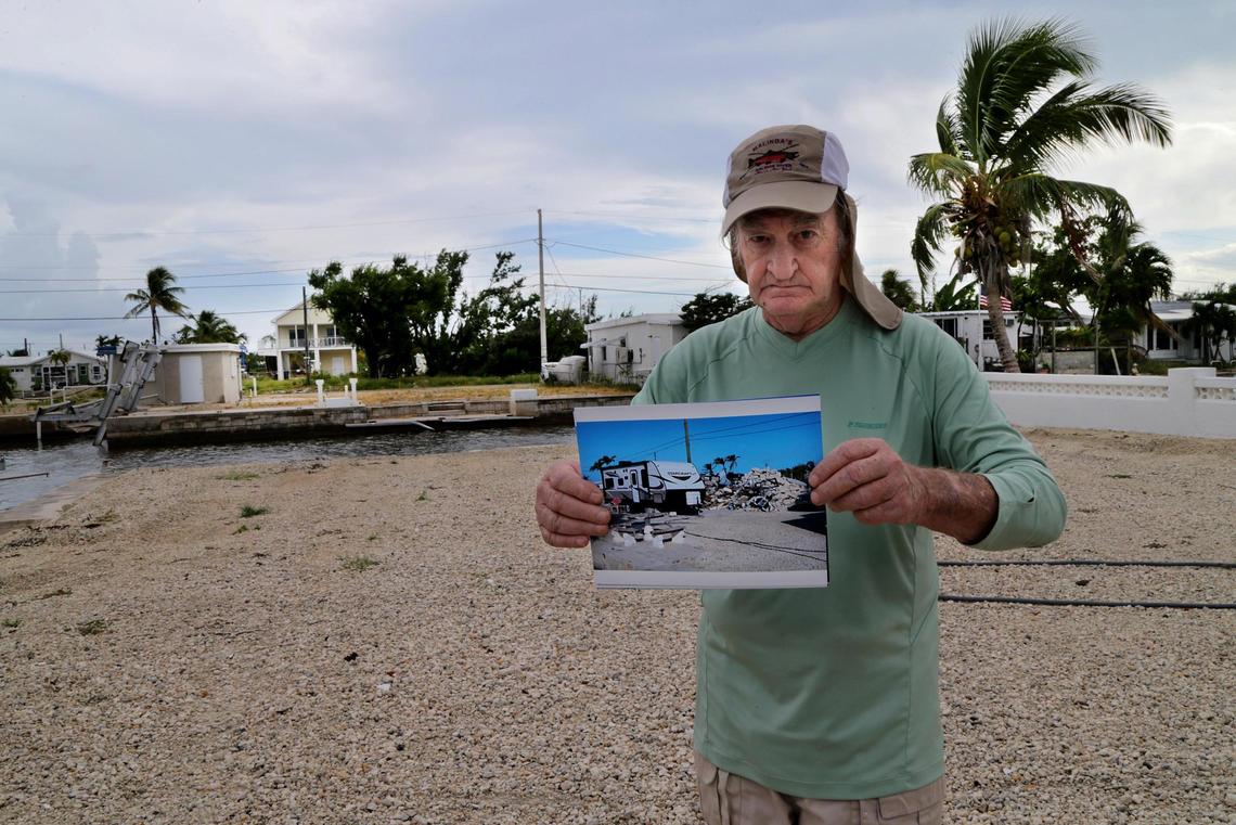 Basil Barna stands in the lot on Big Pine Key where his mobile home used to be before Hurricane Irma destroyed it. He holds a picture on Aug. 29, 2018, of the temporary mobile home he lives in now.