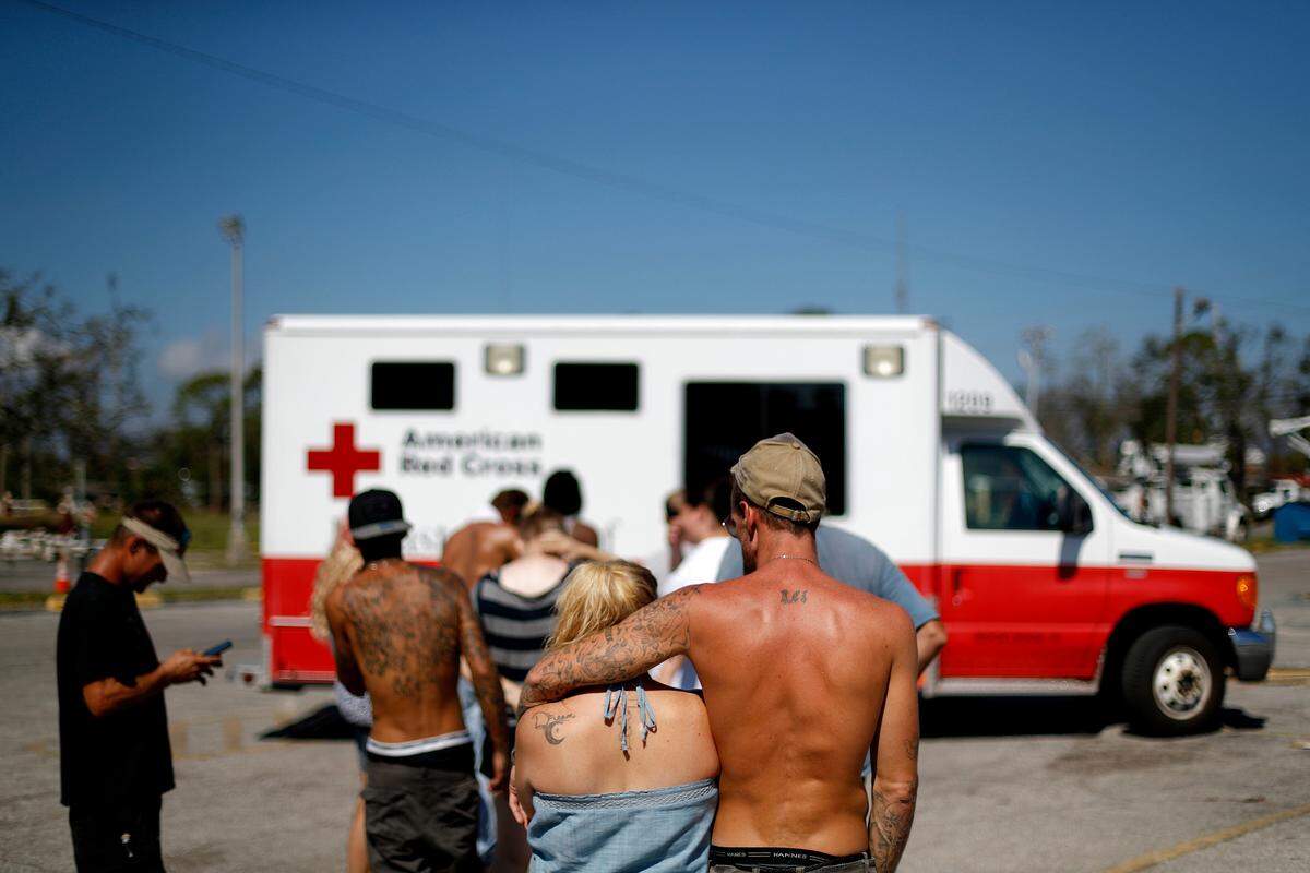 Residents line up for food from the Red Cross outside the damaged motel where many continue to live in the aftermath of Hurricane Michael in Panama City, Tuesday, Oct. 16, 2018.