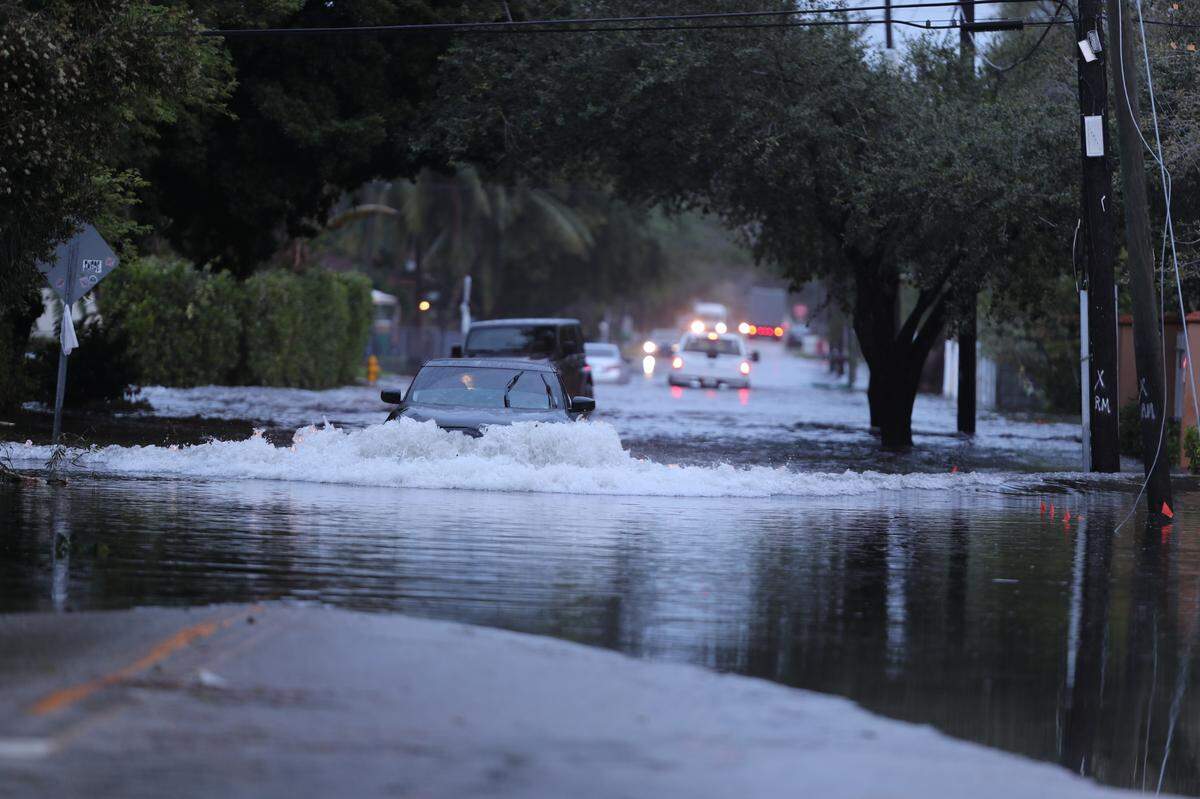 A car pushes its way through deep floodwaters near Northeast 108th Street and Northeast 13th Avenue in North Miami.