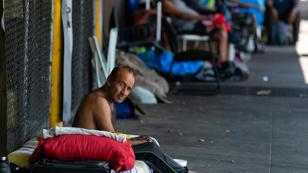 A man sits on the sidewalk on Tuesday, April 14, near South Miami Avenue and Southwest 1st Street in downtown Miami as concerns over the possible spread of COVID-19 worry Miami’s homeless.