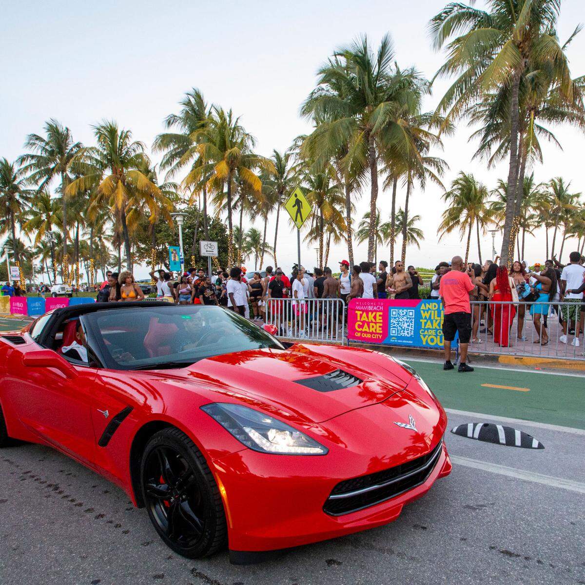 A corvette drives down Ocean Drive alongside crowds filling the sidewalks during Spring Break in Miami Beach, Florida, on Saturday, March 19, 2022.