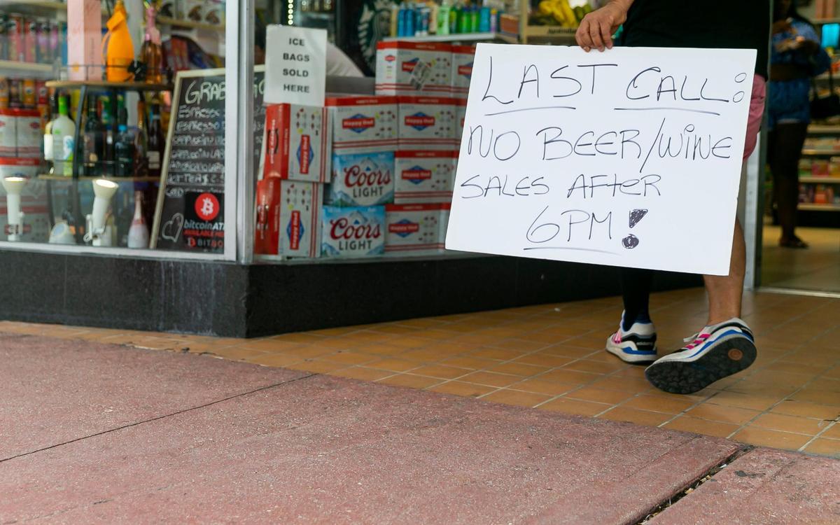 A sign letting customers know they have until 6 p.m. to buy alcohol is on display at a small convenience store off Washington Avenue and 12th Street in Miami Beach, Florida on Friday, March 25, 2022. City officials imposed a midnight curfew and forced stores to stop selling alcohol after 6 p.m. The restrictions were set in place after two shootings in Miami Beach the weekend before caused city officials to announce a “state of emergency.”