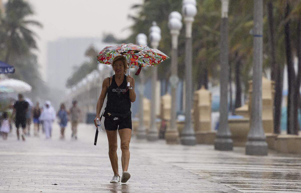 Mary Clare walks down Hollywood Beach Broadwalk as heavy rain makes its way across parts of South Florida on Tuesday.