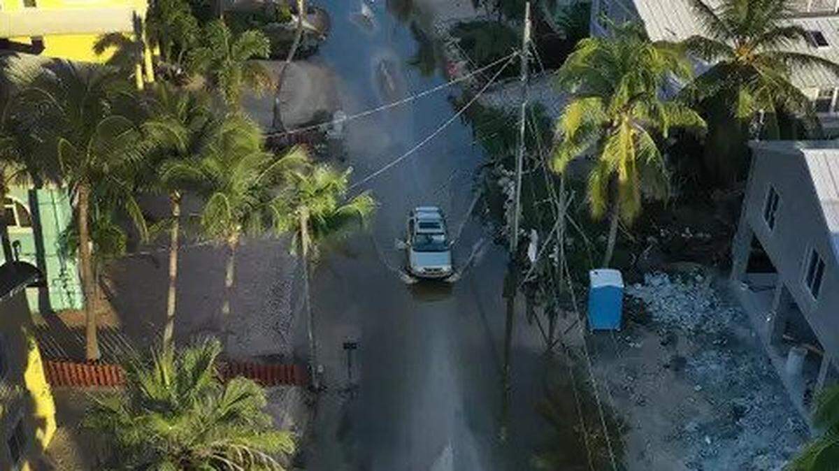 A view from a drone shows, in October, a car as it drives through a street flooded with ocean water in Key Largo.