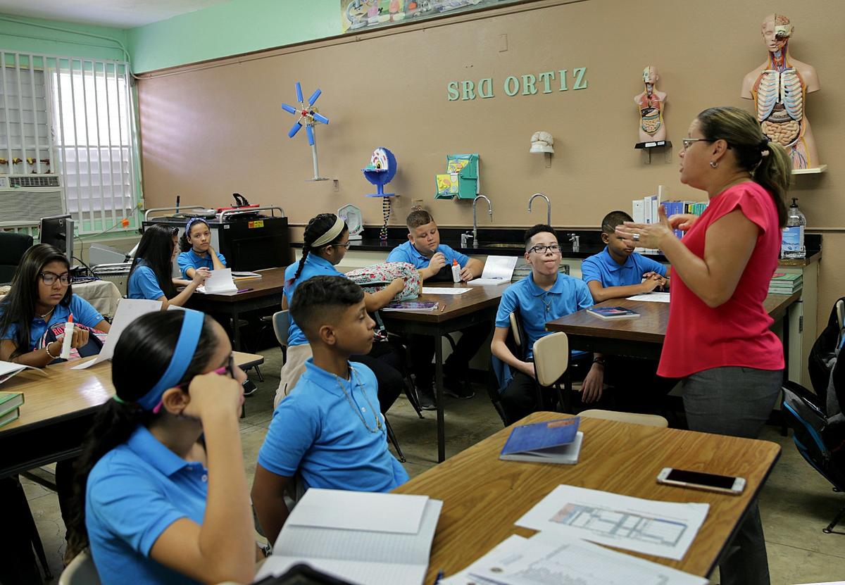 Counselor Isis Vega welcomes seventh-graders at Rosa Costa Valdivieso middle school in the town of Yabucoa on Monday, Aug. 13, 2018, on the first day of classes of a new school year. Hurricane Maria hit Puerto Rico almost a year ago.
