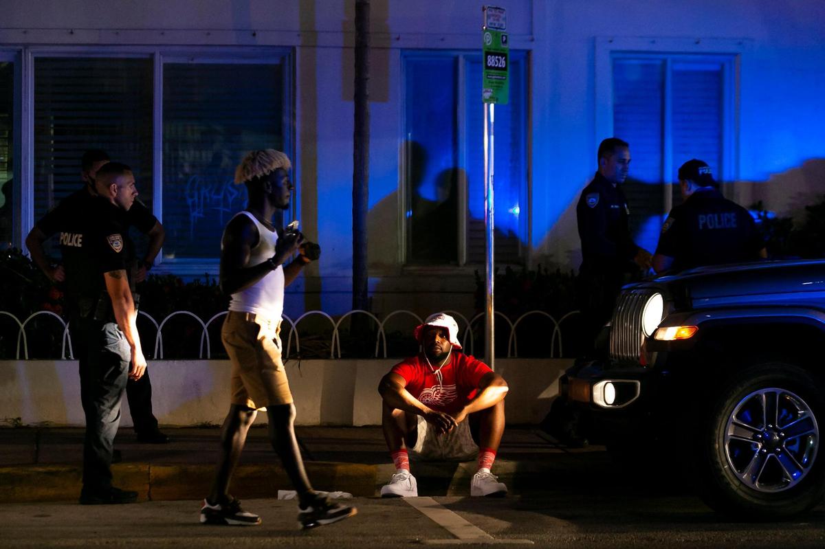 Police officer inspect a vehicle after detaining a man (center-bottom) on Collins Avenue in Miami Beach, Florida on Friday, March 26, 2021.