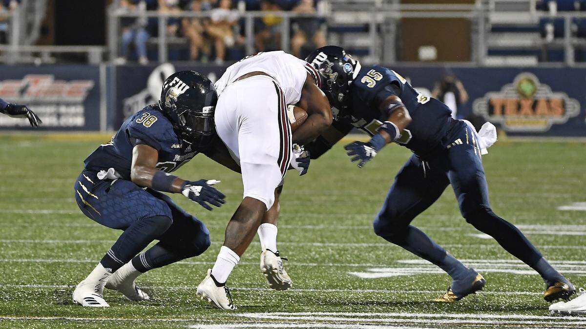 FIU’s Richard Dames (38) and Rishard Dames (35) tackle a University of Massachusetts runner Sept. 15, 2018, at Miami, Florida. FIU won the game 63-24.