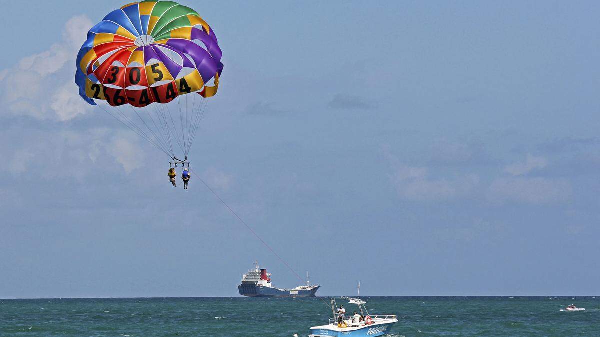 In this Sept. 24, 2012 photo, two people parasail over the Miami Beach,Fla. area. Soaring high above the ocean off South Beach, tethered only by a rope to a boat hundreds of feet below, riding in a parasail is at once exhilarating and oddly peaceful, even quiet. For millions of people, that’s the takeaway from a once-in-a-lifetime experience. But every year there are accidents, some of them fatal. The Parasail Safety Council, which tracks injuries and deaths from the activity nationwide, reports more than 70 people have been killed and at least 1,600 injured between 1982 and 2012, out of an estimated 150 million parasail rides during those 30 years. Despite the inherent risk, few federal or state safety regulations exist for parasailing. In Florida, which has by far the largest number of parasail operators at about 120, repeated efforts to enact new rules following fatal accidents have landed with a thud. Florida is seen by safety proponents as a national bellwether because of parasailing’s popularity in the state.