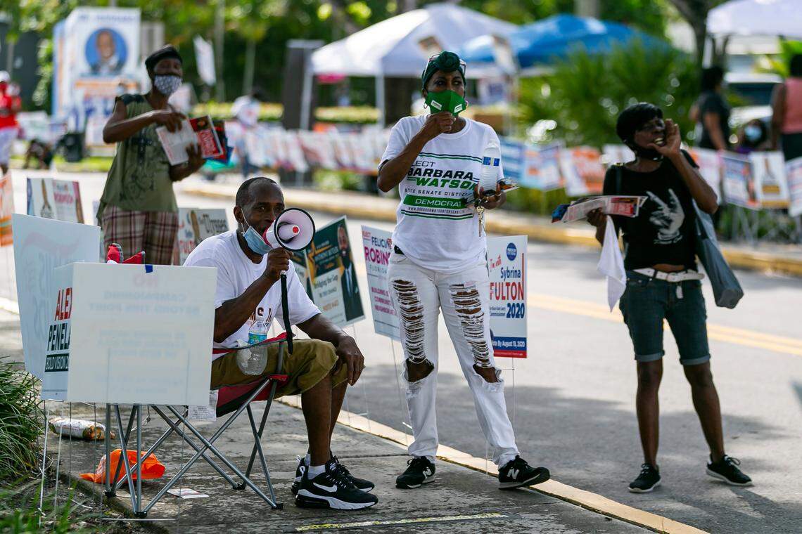 Gary Johnson, 42, bottom left, and Deborah Herring, center, campaign workers, try to encourage voters for their candidates on the first day of early voting during the Florida primary at the North Dade Regional Library in Miami Gardens, Florida, on Monday, Aug 3, 2020. If you don’t like standing in line, it would be good idea to take a chair to your polling place on Election Day.