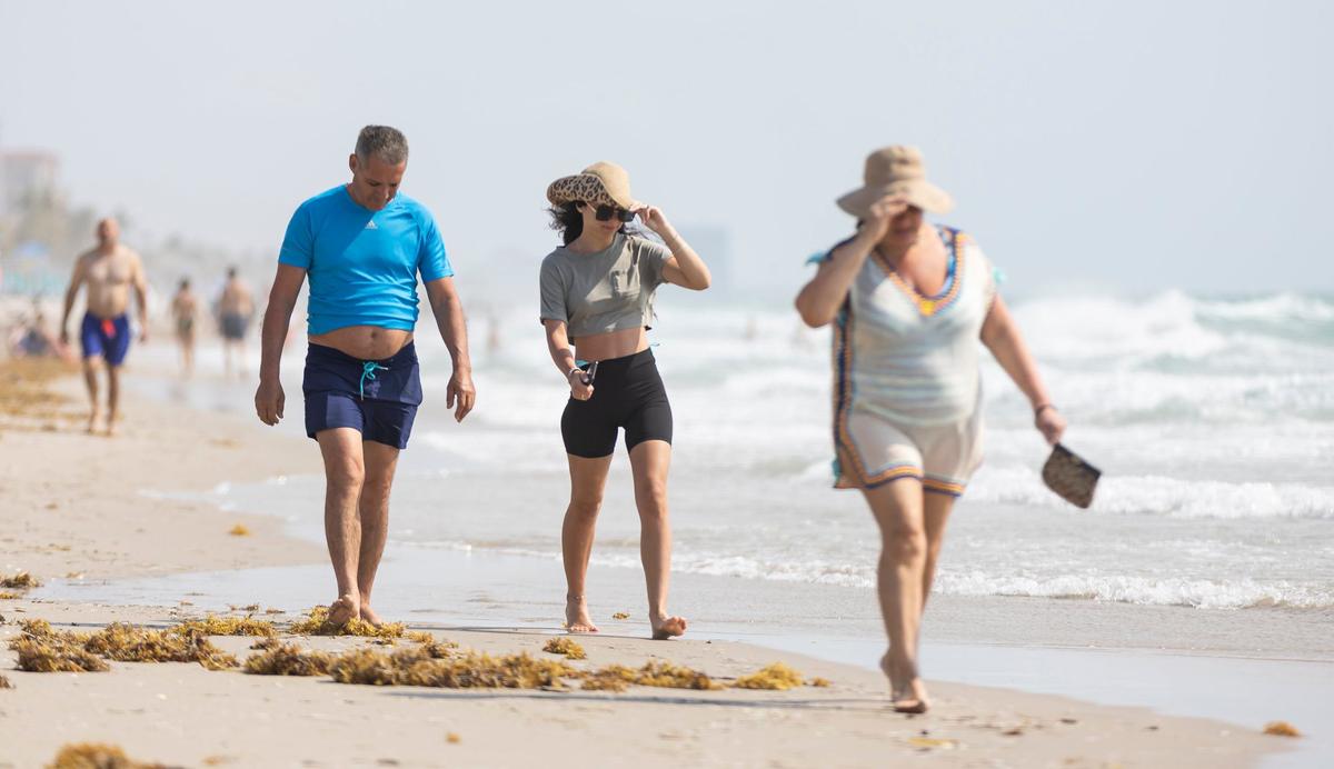 People make their way along the shoreline near the Hollywood Beach Broadwalk as temperatures soar into the 90s on Tuesday, May 14, 2024, in Hollywood, Fla.