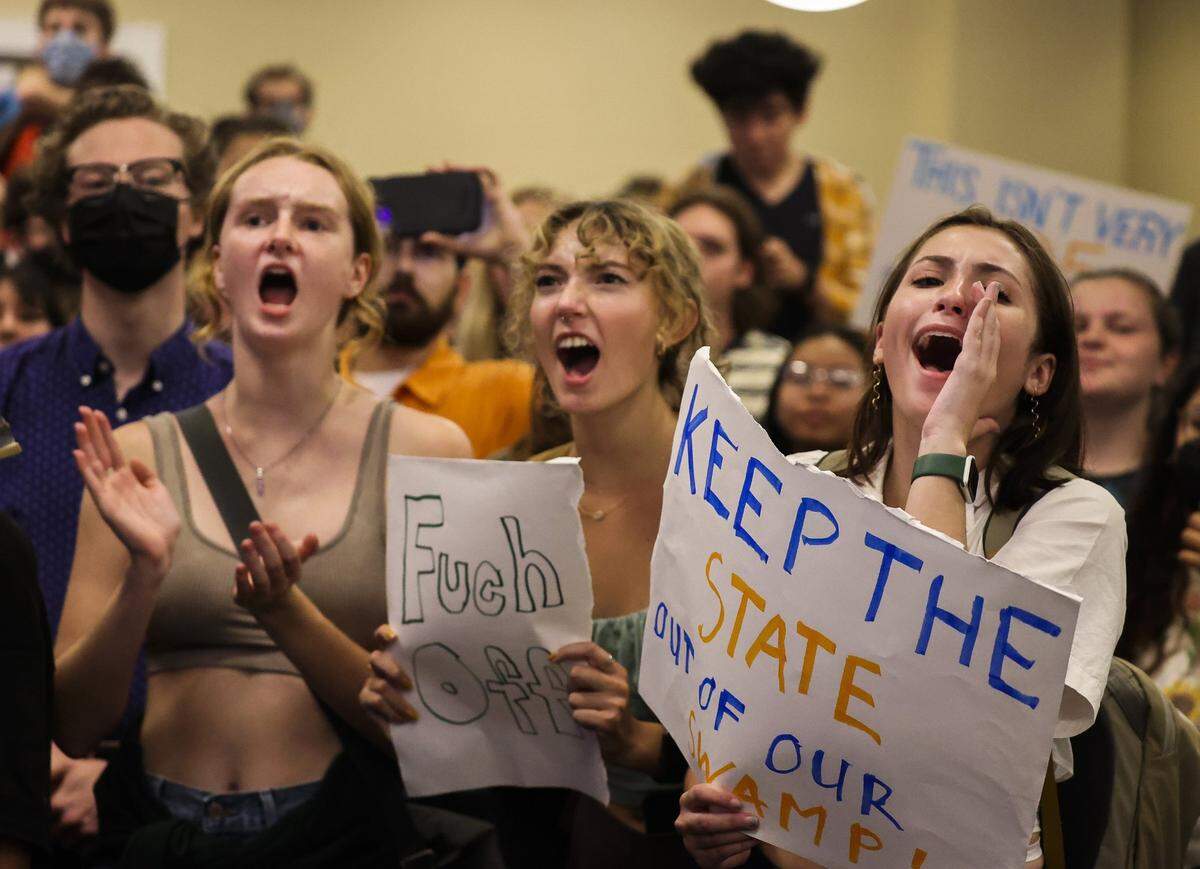 From left, students Josie Maw, Erin Enabnit and Eliza Cave cheer during a protest inside the President’s Ballroom at Emerson Alumni Hall at the University of Florida as U.S. Sen. Ben Sasse of Nebraska was scheduled to speak on Monday, Oct. 10, 2022.