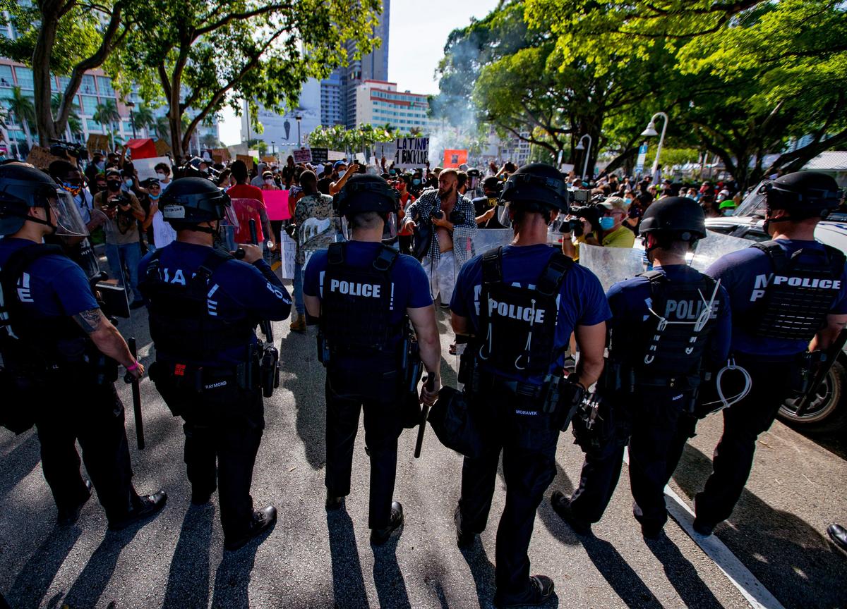Miami-Dade Police Officers hold a defensive line blocking protesters from moving towards Bayside Marketplace during the second day of the “Justice for George Floyd” protests in Downtown Miami, Florida on Sunday, May 31, 2020.