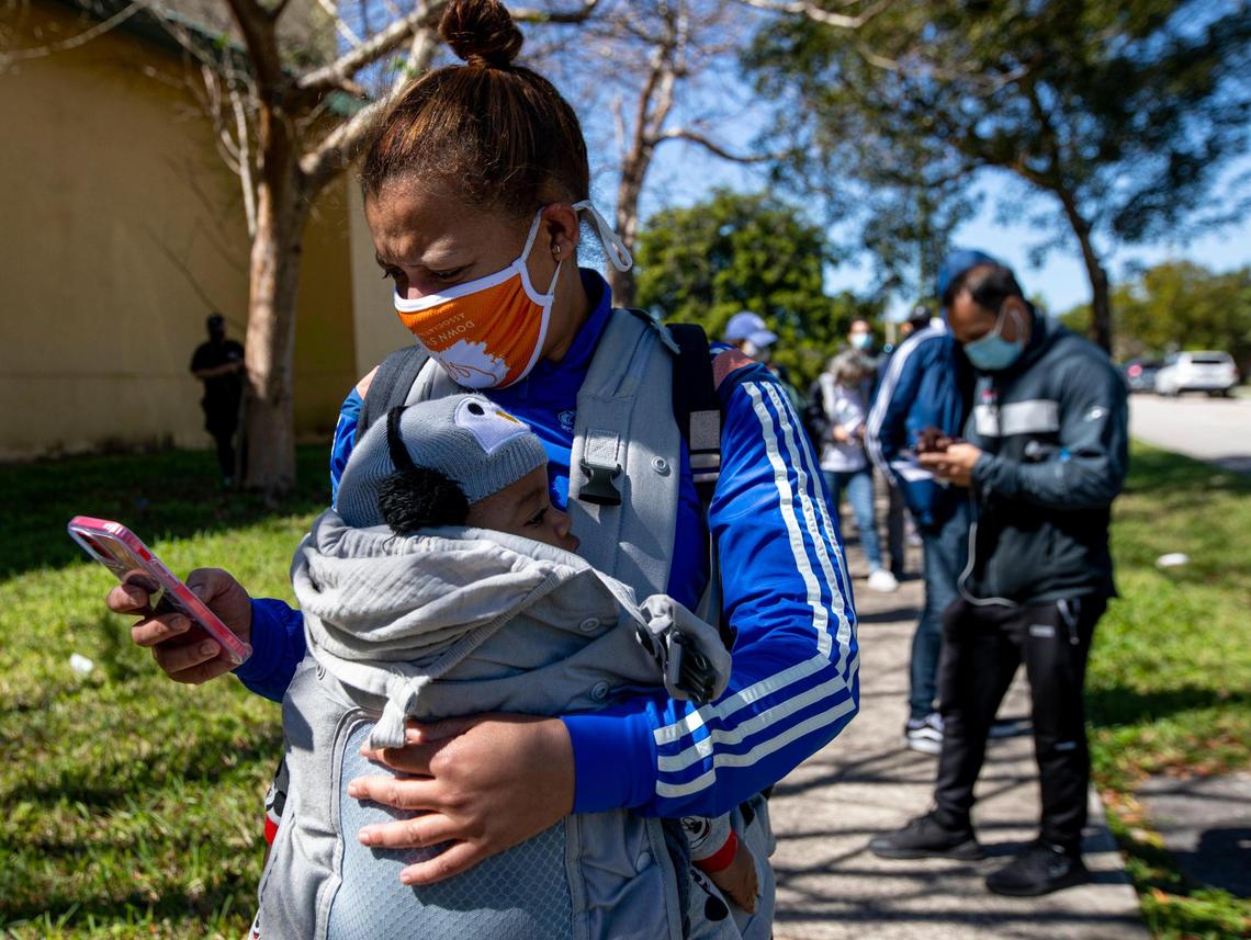 Yasnira Vazquez, 41, holds her six month year old baby, James, in her arms as she waits in line to get vaccinated at the FEMA Florida City Vaccination site located within the Florida City Youth Center in Florida, on Sunday, Mar., 7, 2021. Vazquez works with children with disabilities and obtained a doctors note to get vaccinated despite not meeting state requirements for the first phase of the vaccination .