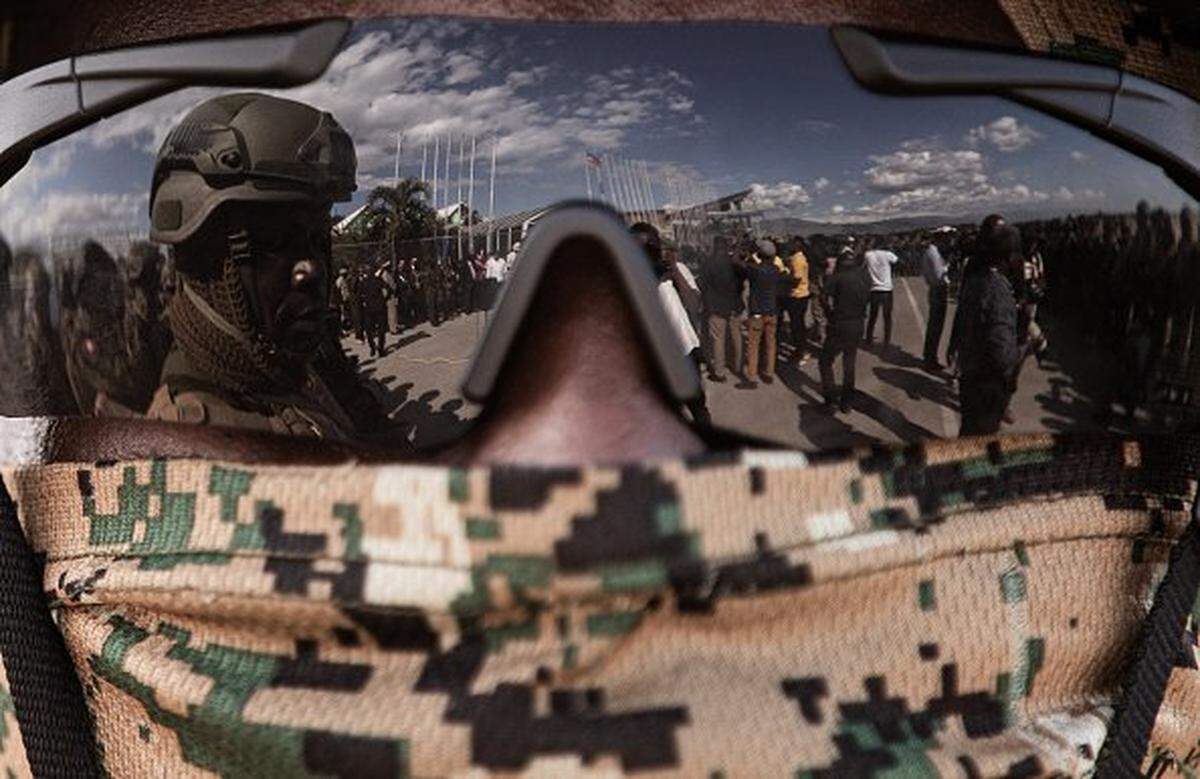 Kenyan police officers are reflected on the glasses of one of their colleagues as they arrive at Toussaint Louverture International Airport in Port-au-Prince, Haiti, on December 8, 2025. Kenya announced on December 8th that it had deployed more than 230 highly specialized police officers. They arrive at a critical moment, following the expansion of the Gang Suppression Force's (GSF) mandate published on October 3, 2025.