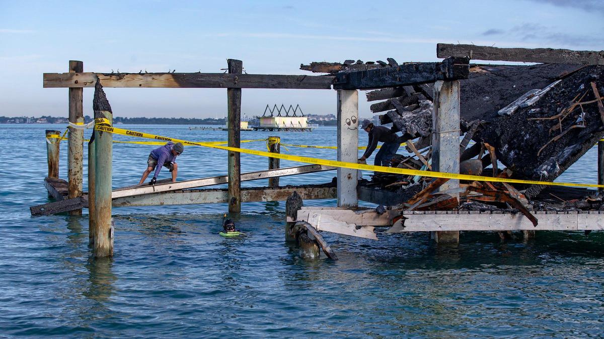 Men remove debris after one of the seven remaining houses at the historic Stiltsville community on Biscayne Bay burned down in January. Today, only six houses remain on Friday, January 15, 2021.
