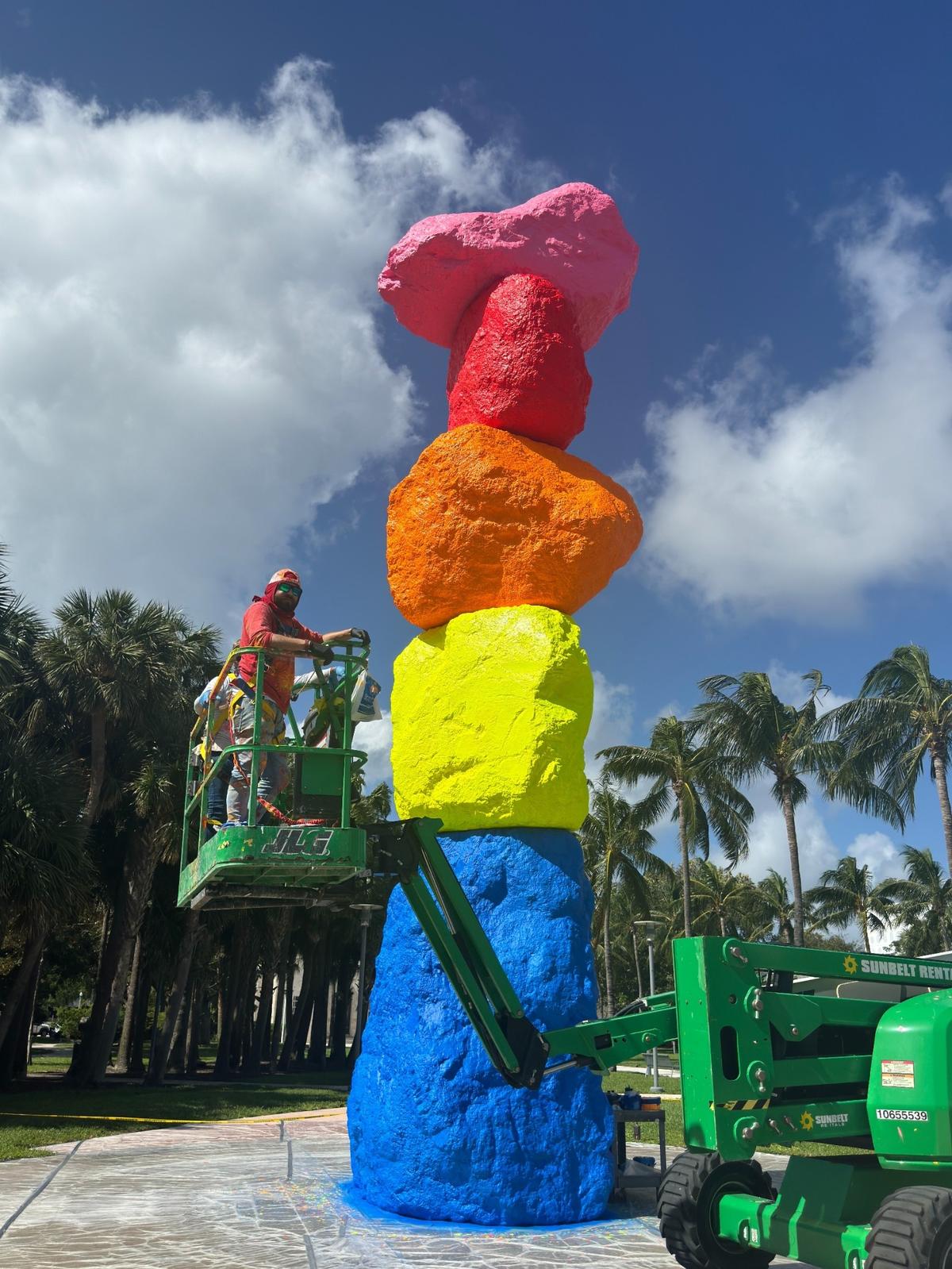 A worker cleans “Miami Mountain,” a towering rainbow totem by artist Ugo Rondinone which was installed in front of the Bass Museum in Miami Beach in 2016 for Art Week.