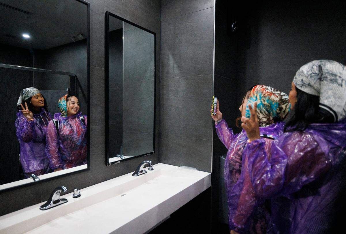 Norma, right, and Gracia take cover from the rain in the Bayside Marketplace bathroom when Ultra shut down their entrances during the third day of Ultra Music Festival on Sunday, March 30, 2025, at Bayfront Park in downtown Miami, Fla. 